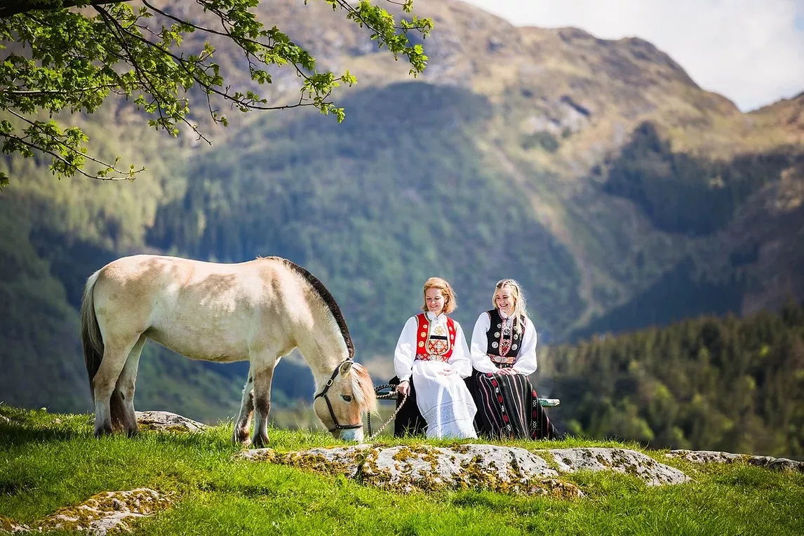 traditionally clothed norwegian women on mountainside with horse