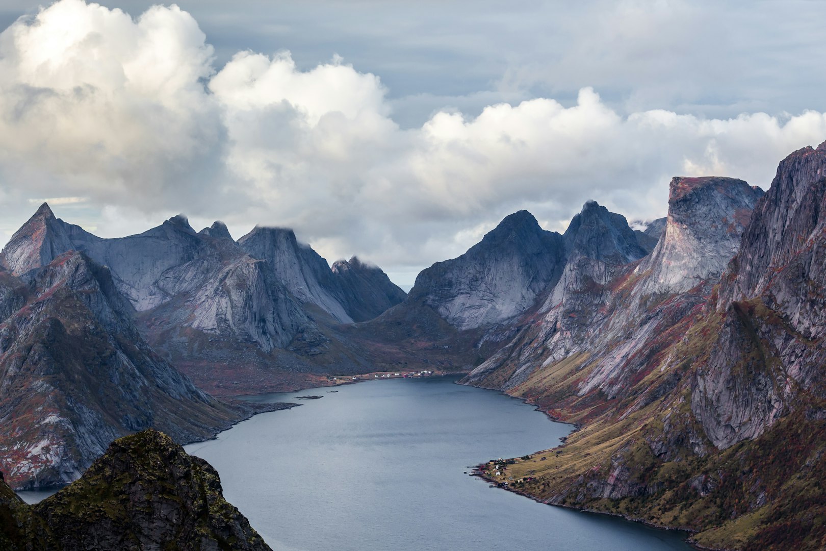 Hiking in Norwegian autumn near a body of water surrounded mountain peak at Reinebringen, Norway