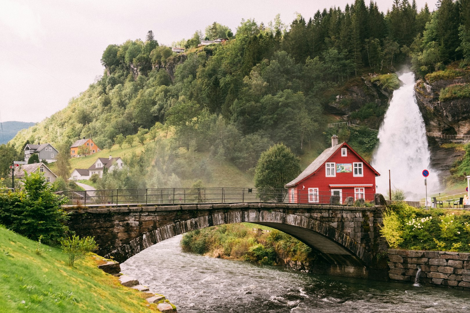 The view of a red house sitting on top of a lush green hillside at Steinsdalsfossen in Norway