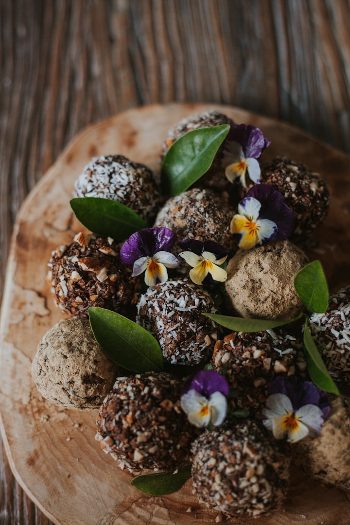 Raw Oatmeal Balls - a wooden plate topped with chocolate balls covered in flowers