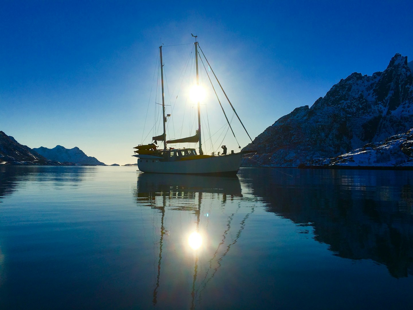 Sun setting behind sailboat in a Norwegian Fjord